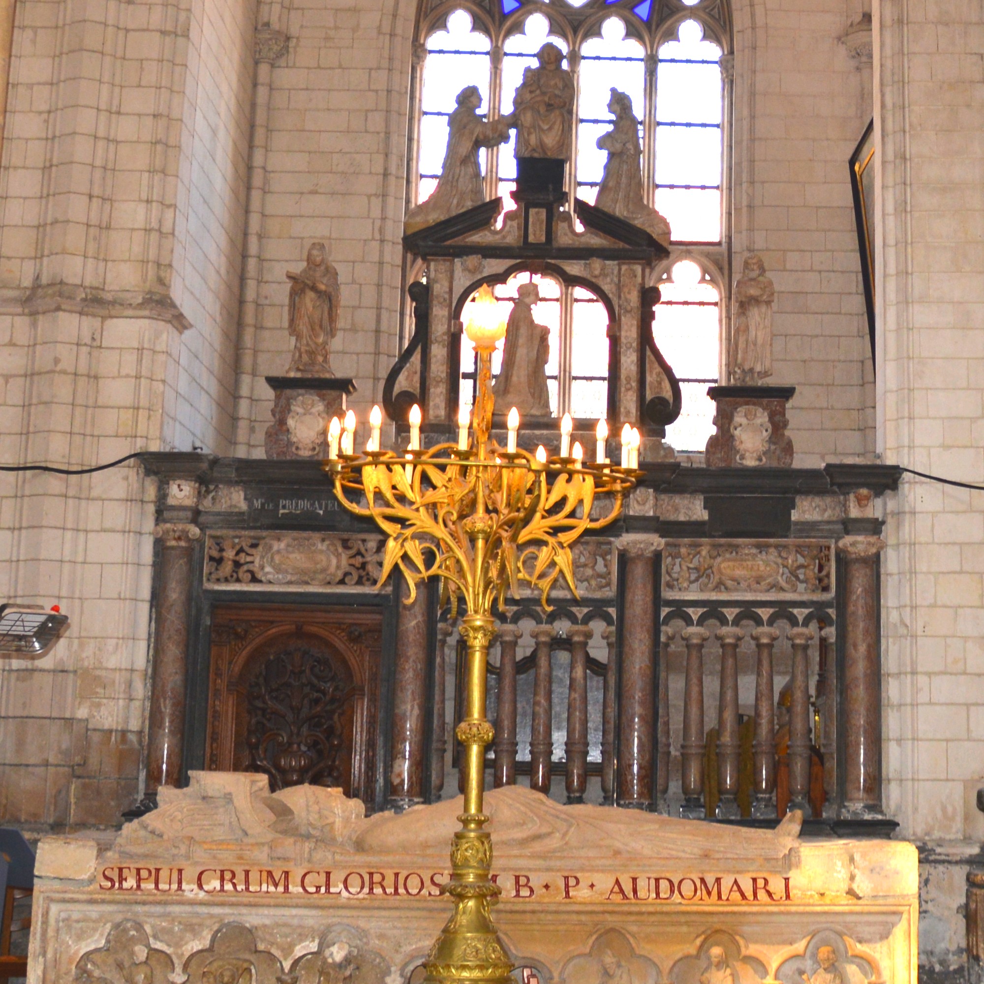 Cathédrale de Saint-Omer - Chapelle Saint Jacques Apôtre, La clôture de 1634 est monumentale. Au sommet la Très Sainte Vierge ayant à sa droite un de ses grands serviteurs, le Bienheureux  Hermann  Joseph,  de l'ordre de Prémontré au X   ème  siècle et patron du chanoine donateur Hermann Lœmel que l'on voit lui-même  à genoux  dans une grande arcade ajourée.